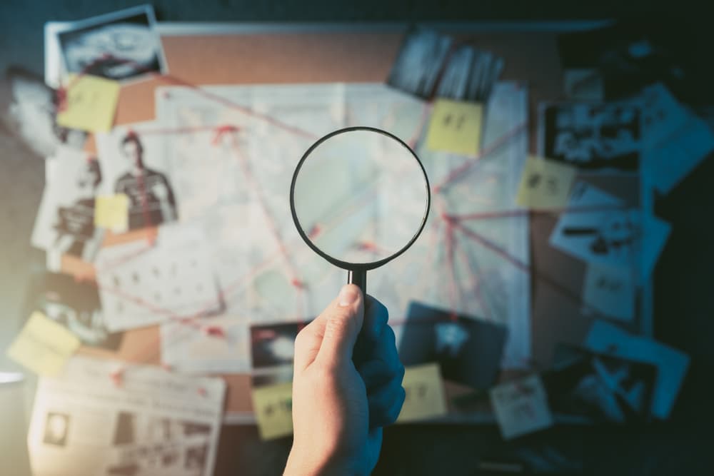Magnifying glass in front of a board with evidence